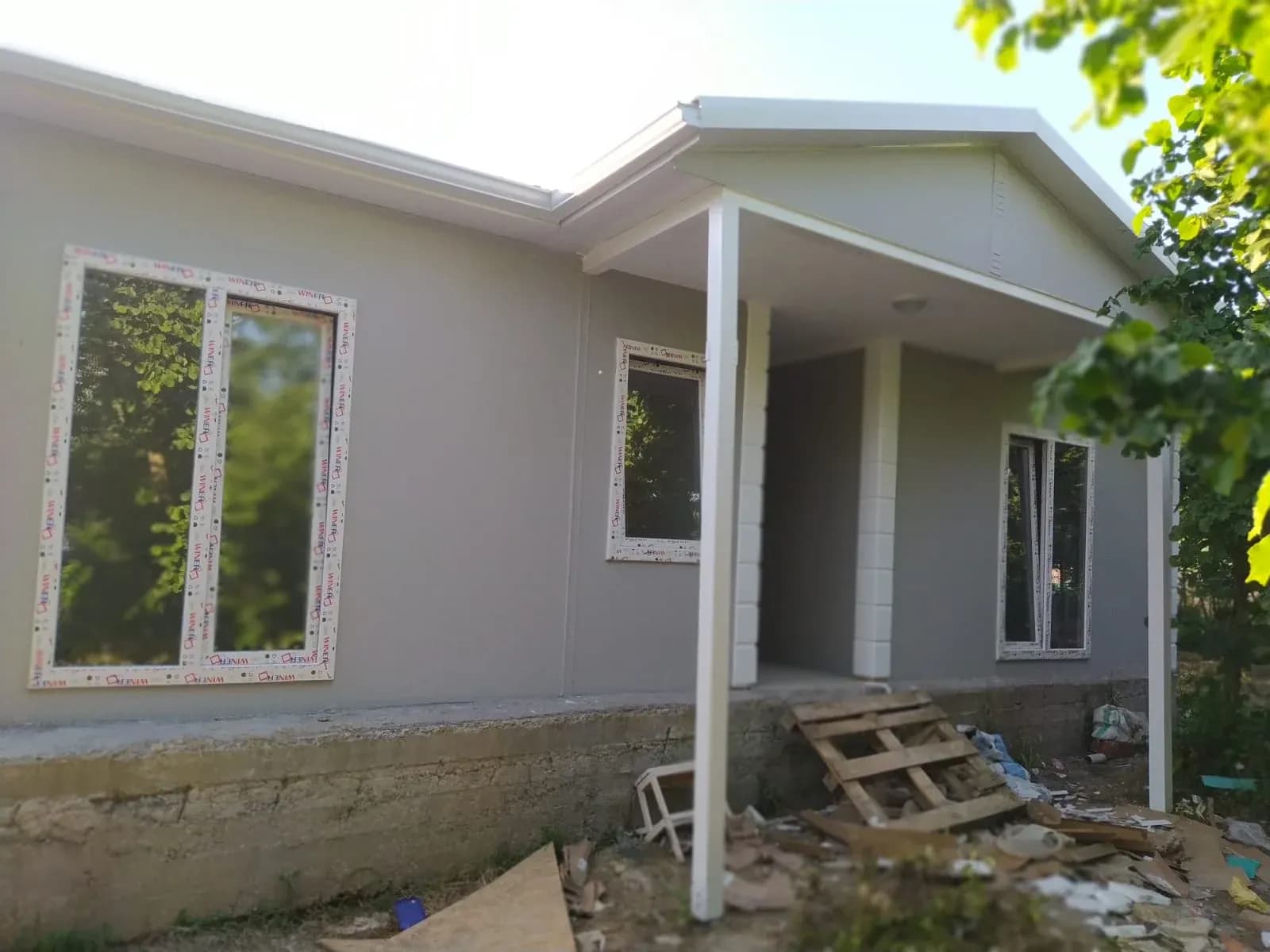 Bej cepheli prefabrik evin verandası ve giriş cephesi