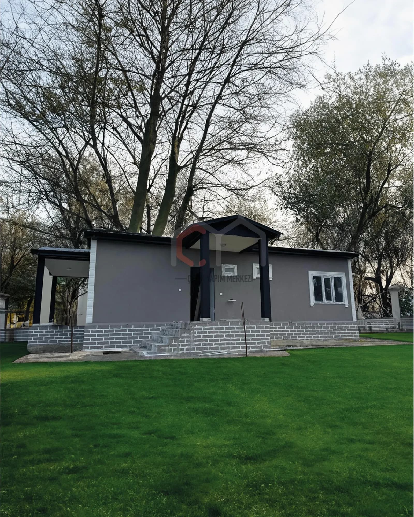 Gri cepheli, kolonlu girişli tek katlı prefabrik ev ve bahçesi