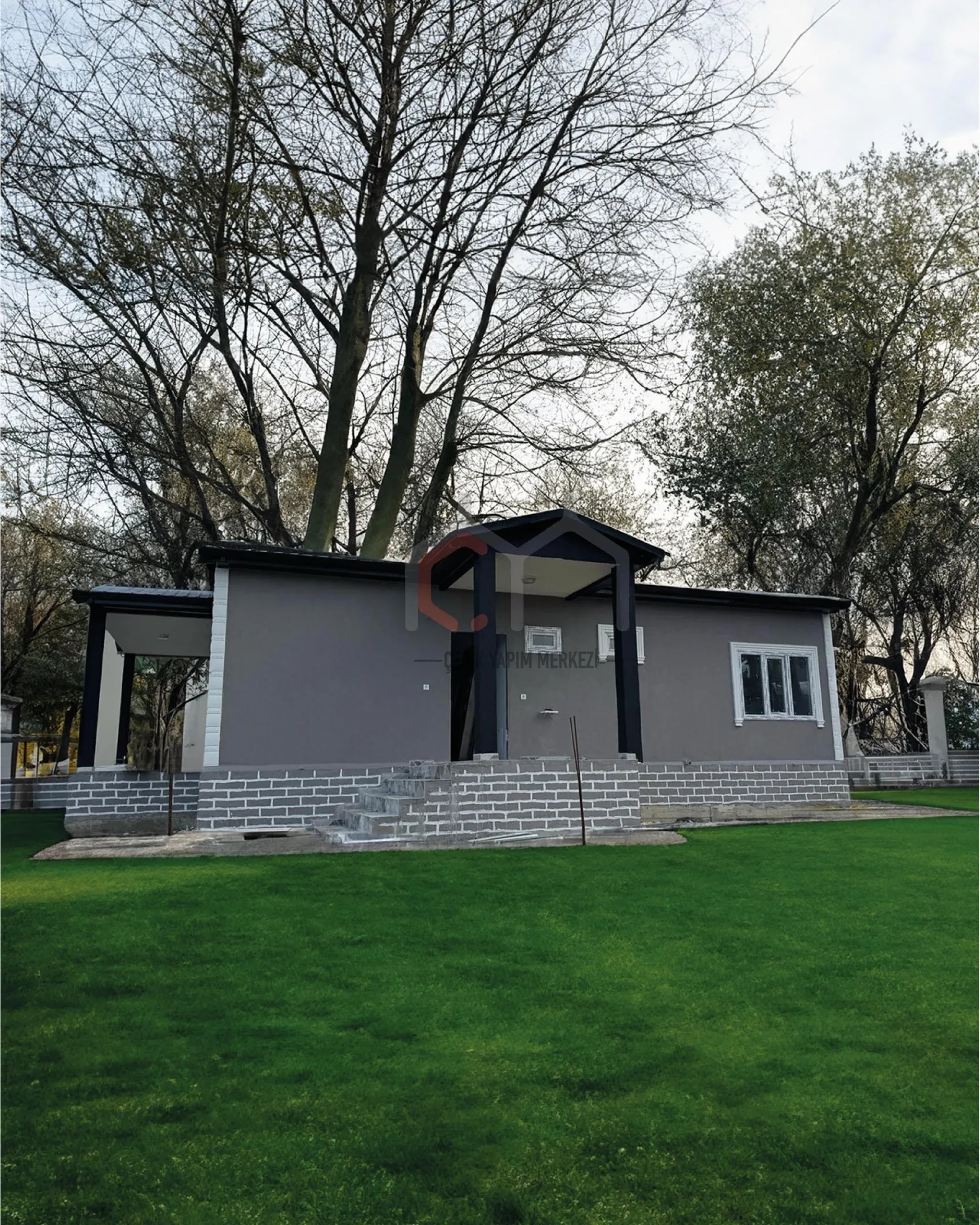 Gri cepheli, kolonlu girişli tek katlı prefabrik ev ve bahçesi
