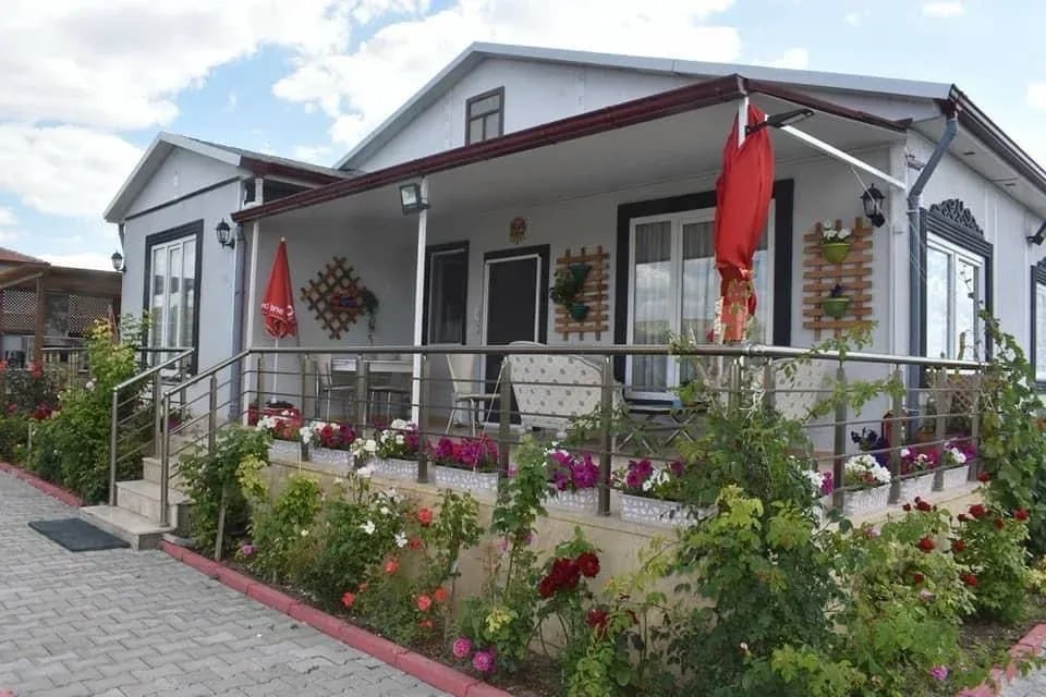 Verandası çiçeklerle düzenlenmiş, kullanımdaki tek katlı prefabrik ev